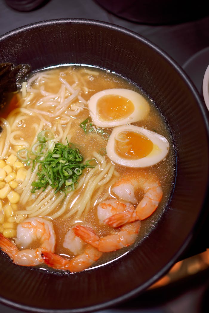 Mouthwatering shrimp ramen with soft-boiled egg, corn, and scallions in savory broth.