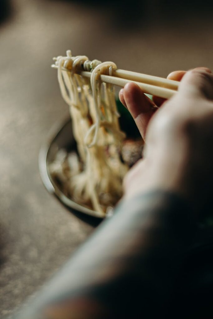 Appetizing close-up image of noodles being lifted with chopsticks, showcasing culinary delight.